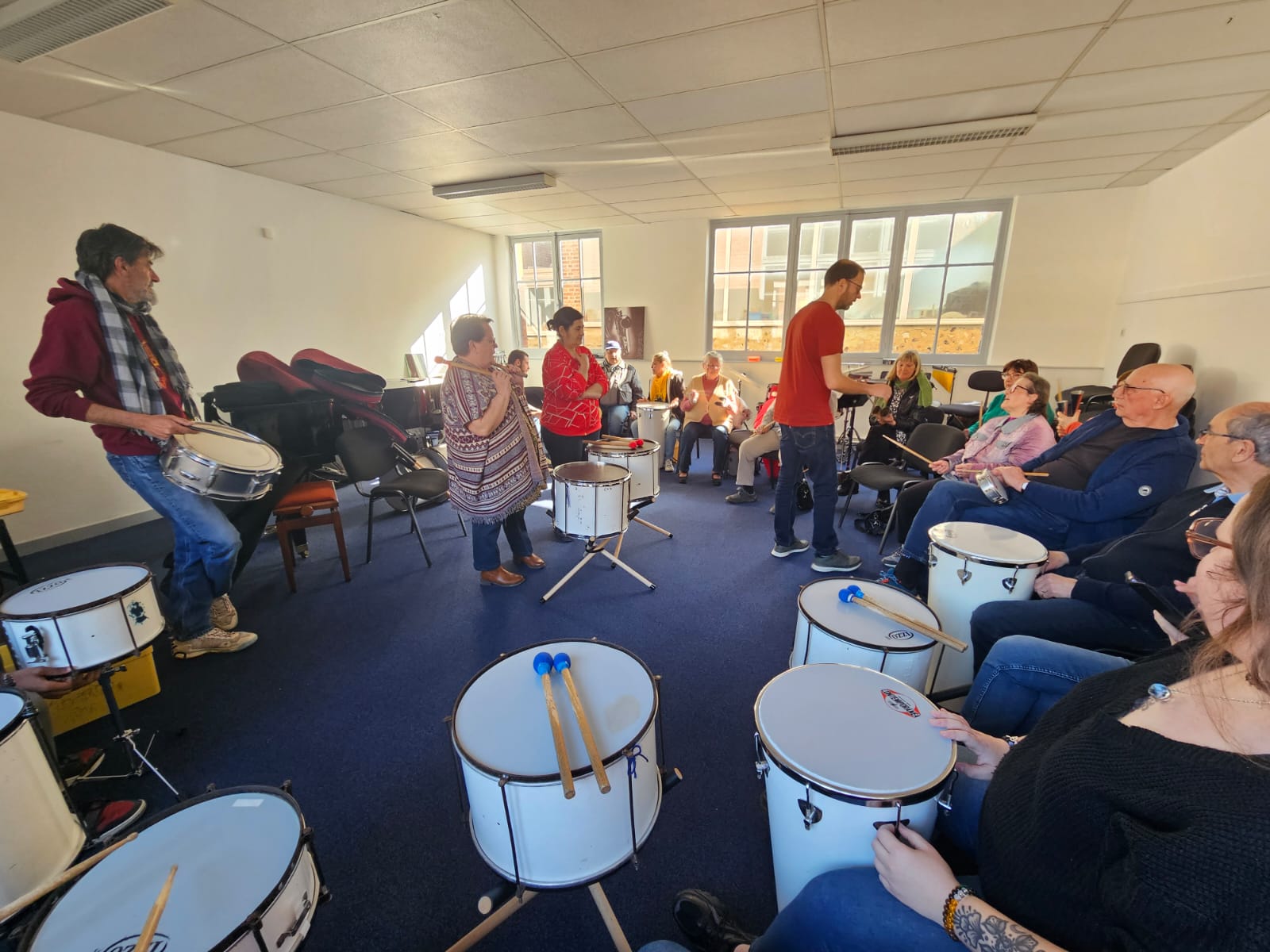 Atelier percussion avec des seniors jouant du tambour en cercle