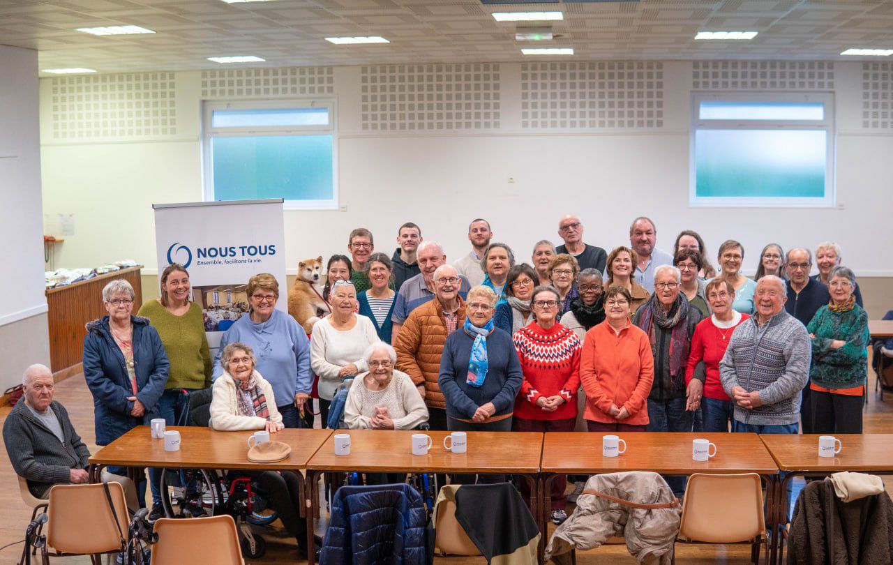 Photo de groupe officielle devant le banner Nous Tous